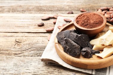 Organik kakao yağı, çikolata parçaları, fasulye ve toz ahşap masa, yakın plan. Metin için boşluk
