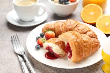 Nefis bir kahvaltı. Açık gri masada reçelli, dutlu ve kahveli lezzetli kruvasanlar, yakın plan.