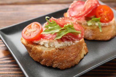 Salamlı, krem peynirli, ahşap masadaki domatesli nefis bruschettalar.