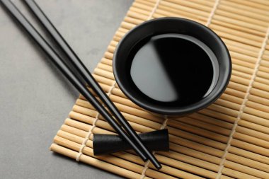 Soya sosu kasede ve çubuklar gri masada, yakın plan.