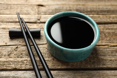 Soya sosu kasede ve çubuklar ahşap masada, yakın plan.