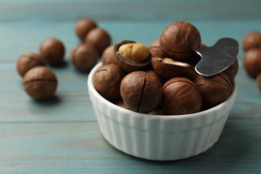 Macadamia cevizleri ve metal anahtar açık mavi ahşap masada, yakın plan.