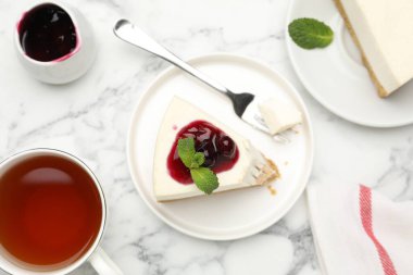 Kiraz reçelli lezzetli bir cheesecake ve beyaz mermer masada servis edilen nane şekeri.