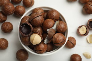 Macadamia fındıkları ve metal anahtar beyaz masada, düz yerde.