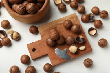 Macadamia fındıkları ve metal anahtar beyaz masada, düz yerde.