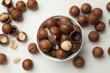 Macadamia fındıkları ve metal anahtar beyaz masada, düz yerde.