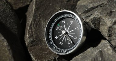 Taşların üzerinde modern bir pusula, yakından görüş.