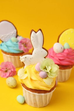 Turuncu arka planda Paskalya dekoru olan lezzetli kekler, yakın plan.