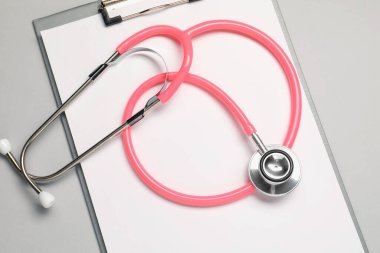Açık gri arkaplanda stetoskop ve pano, üst görünüm