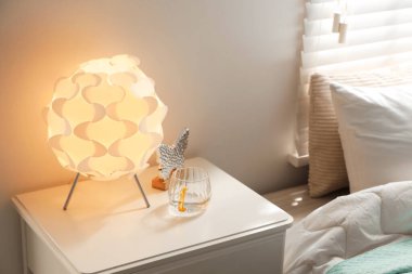 Şık lamba, dekoratif kelebek ve evdeki komodinin üzerinde su olan bardak.