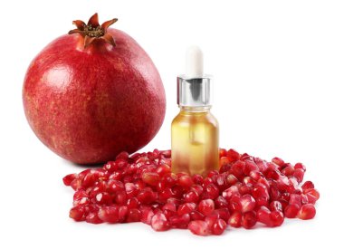 Bir şişe gerekli yağ, taze nar ve beyaz üzerine izole edilmiş tohumlar.