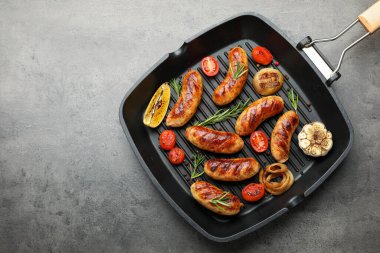Izgara sosis, domates ve biberiye gri masada ızgara tavada servis edilir. Metin için boşluk