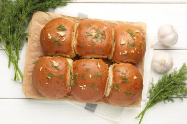 Sarımsaklı taze çörekler ve beyaz ahşap masa üzerinde dereotlar.