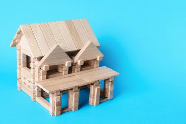 Açık mavi arka planda tahta bloklardan yapılmış bir ev. Metin için boşluk