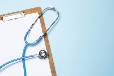 Açık mavi arka planda steteskop ve pano, üst manzara. Metin için boşluk