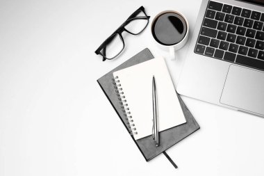 Laptop, kırtasiye malzemeleri, beyaz arka planda bardaklar ve kahve, düz yatak. Metin için boşluk