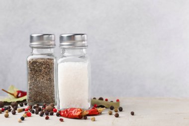 Açık gri masada baharatlı tuzluk ve biberlikler, yakın plan. Metin için boşluk