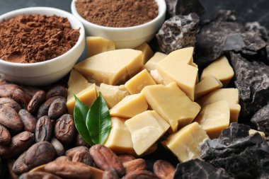 Organik kakao yağı, fasulye, çikolata parçaları, masada toz ve yeşil yapraklar, yakın plan.