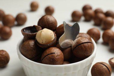 Macadamia fındıkları ve metal anahtar beyaz masada, yakın plan.