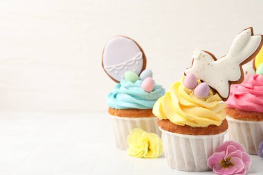 Lezzetli Paskalya çörekleri ve çiçekler beyaz fayanslı masada, yakın plan. Metin için boşluk