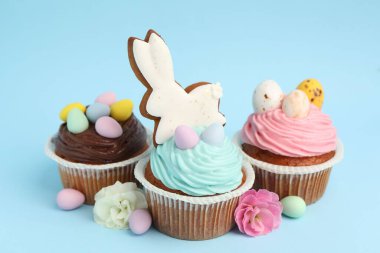 Açık mavi arkaplanda Paskalya dekoru olan lezzetli kekler, yakın plan.