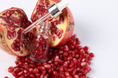 Tohumlu şişe, pipetli ve beyaz zemin üzerinde taze nar, yakın plan.