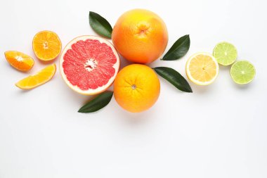 Farklı taze narenciye meyveleri ve beyaz arka planda yeşil yapraklar.