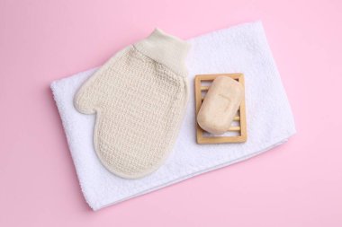 Pembe arka planda duş eldiveni ve sabun çubuğu, düz uzanma