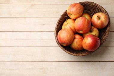Tahta masadaki hasır sepette taze elmalar, üst manzara. Metin için boşluk