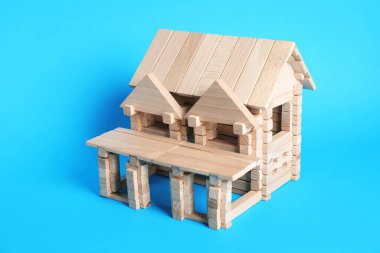 Açık mavi arka planda tahta bloklardan yapılmış ev