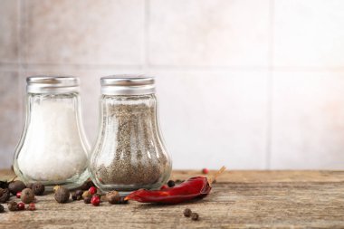 Ahşap masada baharatlı tuzluklar ve biberlikler bulanık arka planda, yakın plan. Metin için boşluk