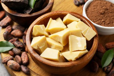 Organik kakao yağı, çikolata parçaları, fasulye, toz ve yeşil yapraklar masada, yakın plan.