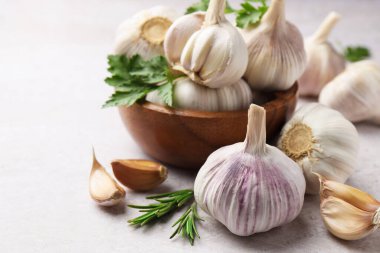 Taze sarımsak, biberiye ve maydanoz açık gri masada, yakın plan.