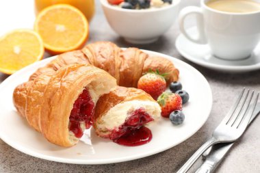 Nefis bir kahvaltı. Açık gri masada reçelli, dutlu ve kahveli lezzetli kruvasanlar, yakın plan.
