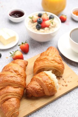 Nefis bir kahvaltı. Lezzetli kruvasanlar, böğürtlenler, yulaf ezmesi ve kahve açık gri masada, yakın plan.