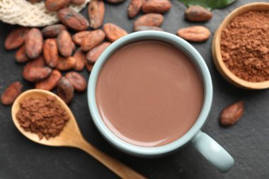 Bardaktaki lezzetli kakao, fasulye ve toz koyu gri masada, düz uzanmış