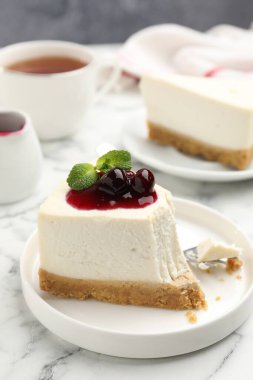 Kiraz reçelli lezzetli bir cheesecake ve beyaz mermer masada servis edilen nane şekeri.