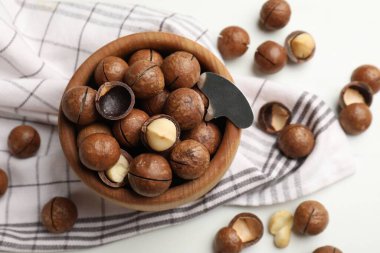 Macadamia fındıkları ve metal anahtar beyaz masada, düz yerde.