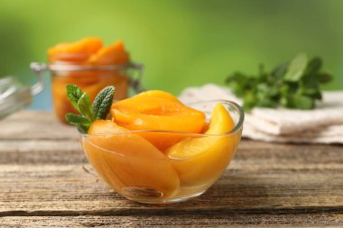 Şeftali turşusu ve nane yaprakları ahşap masada, yakın plan.