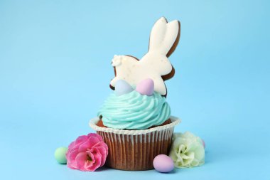 Açık mavi arkaplanda Paskalya dekoru olan lezzetli kek, yakın plan.