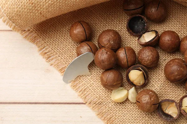 Macadamia fındığı ve metal anahtar açık ahşap masada, düz yerde. Metin için boşluk