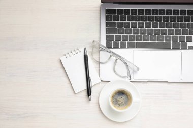 Laptop, kırtasiye malzemesi, kahve ve bardaklar açık ahşap masa, düz yatak. Metin için boşluk