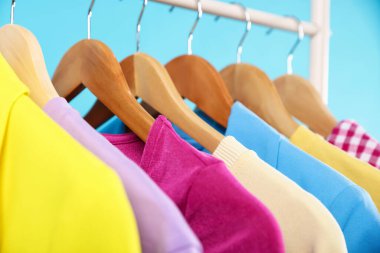 Açık mavi arkaplanda asılı farklı giysiler, yakın plan