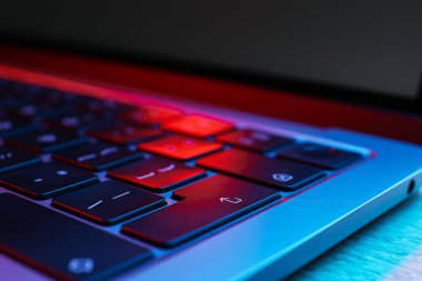 Modern dizüstü bilgisayar ahşap masa üzerindeki neon ışıklarda, yakın plan