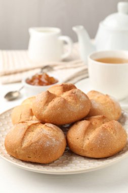 Taze çörekler, reçel ve çay beyaz masada, yakın plan.