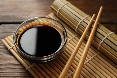 Soya sosu kasede ve çubuklar ahşap masada, yakın plan.