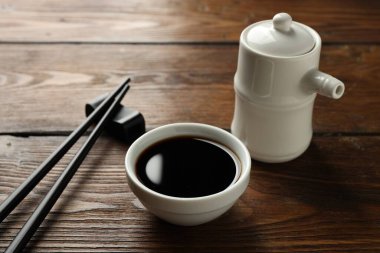 Soya sosu ve yemek çubukları ahşap masada, yakın plan.