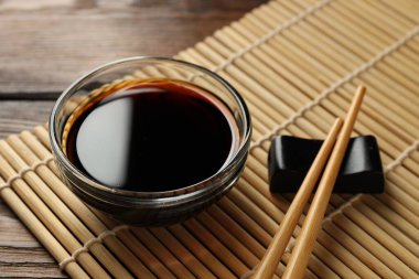 Soya sosu kasede ve çubuklar ahşap masada, yakın plan.