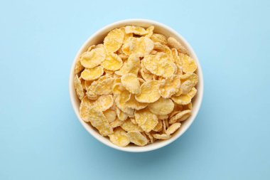 Açık mavi arka planda kasede lezzetli mısır gevrekleri, üst manzara.