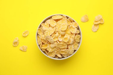 Sarı arka planda kasede lezzetli mısır gevrekleri, üst manzara.